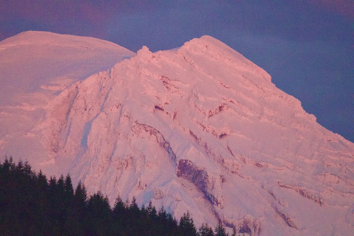 Snow covered top of Mt. Rainier in a pink sunset hue